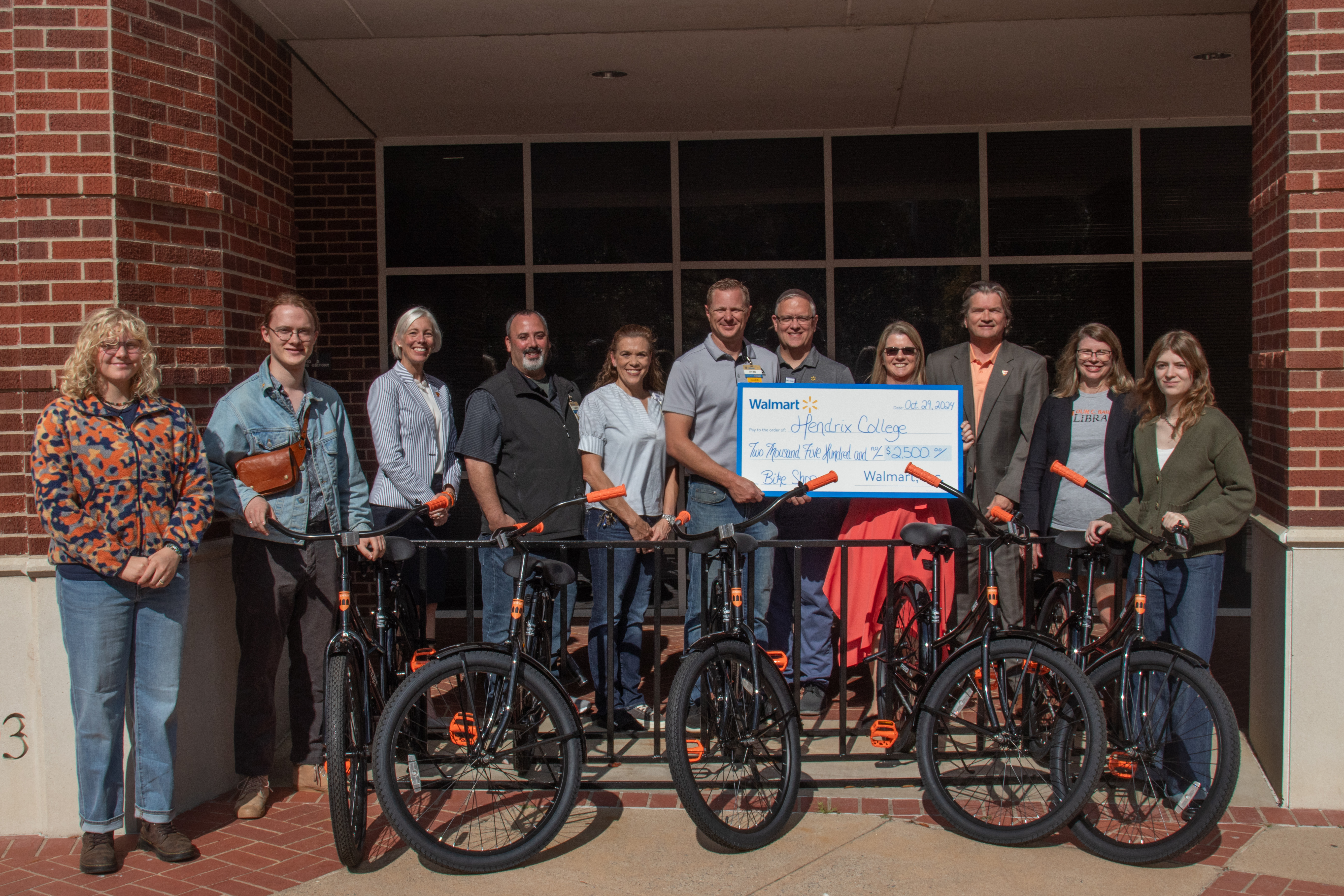 Members of the Hendrix Bike Revolution student organization, Bailey Library faculty, and Hendrix administration gather with Walmart representatives to celebrate the new bicycles ready for use by Hendrix students. From left: Avery Meyer ’28, Ted Bjurlin ’25, Hendrix Vice President for Advancement Meredith Brunen; local Walmart managers Gary Nason, Andrea Newman, and Ryan Peters; Michael Lindsey of the Walmart Foundation; Hendrix President Karen Petersen, Assistant Vice President for Development Ben Carter, Director of the Library Britt Anne Murphy, and Amelia Lindsey ’25. 